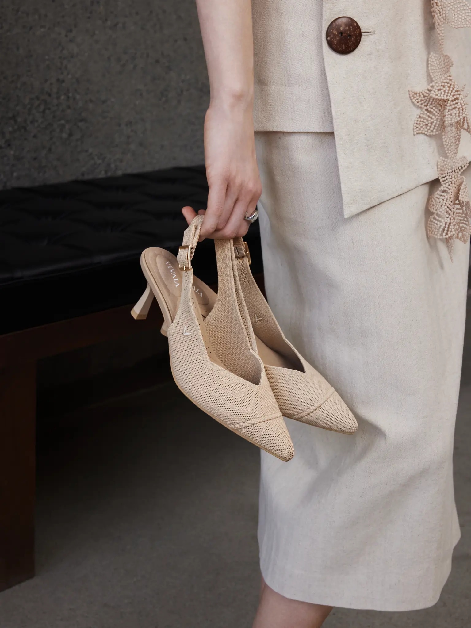 Woman holding VIVAIA Addison slingback heels in professional outfit