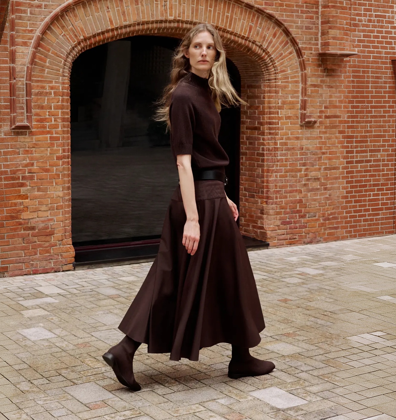 Model wearing Dark Chocolate square-toe ankle boots outside a brick city building