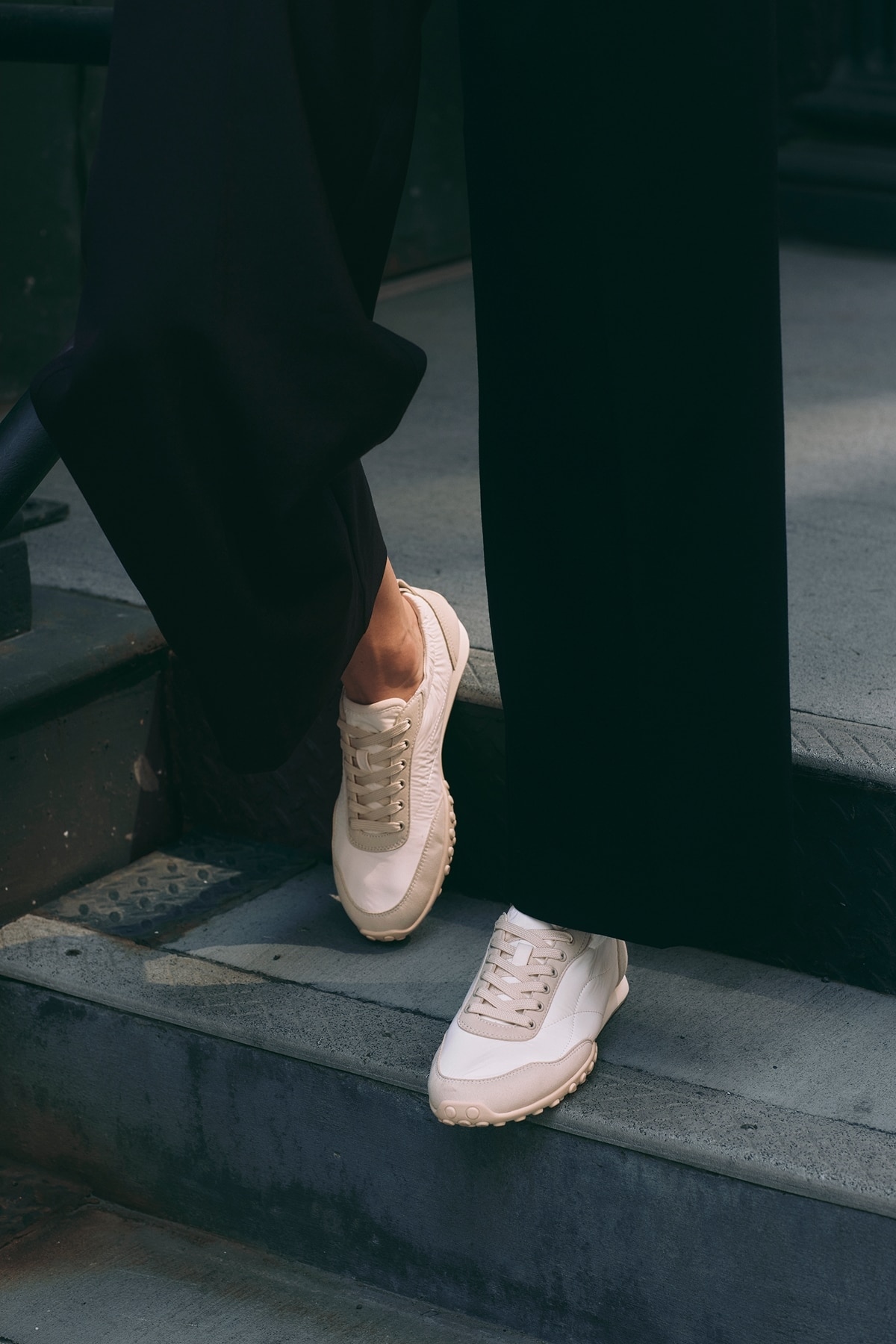 Detalle de zapatillas claras sobre escalones urbanos