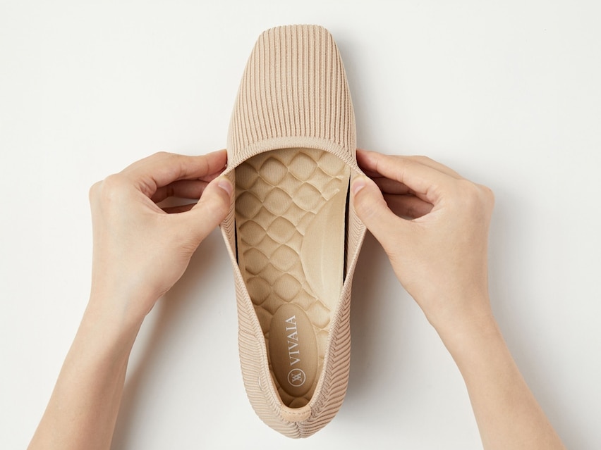 Hand pressing stretchy knit upper of VIVAIA heel showing flexibility