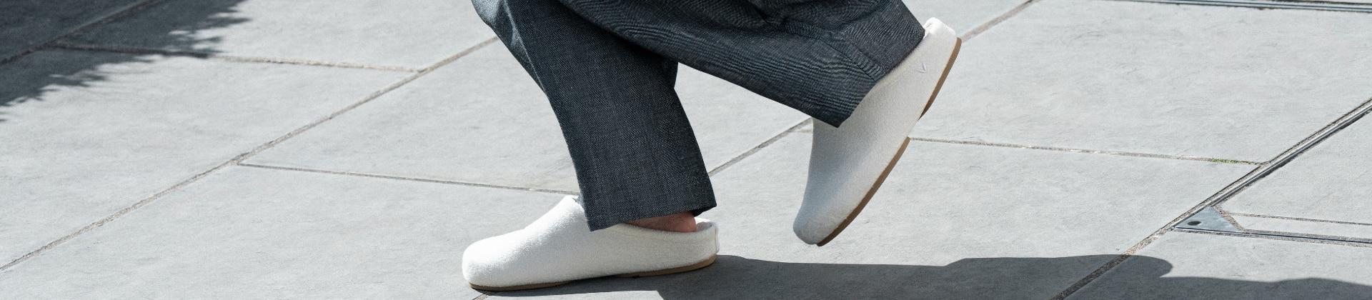 White Round-Toe Clog Mules in motion on a sunlit sidewalk
