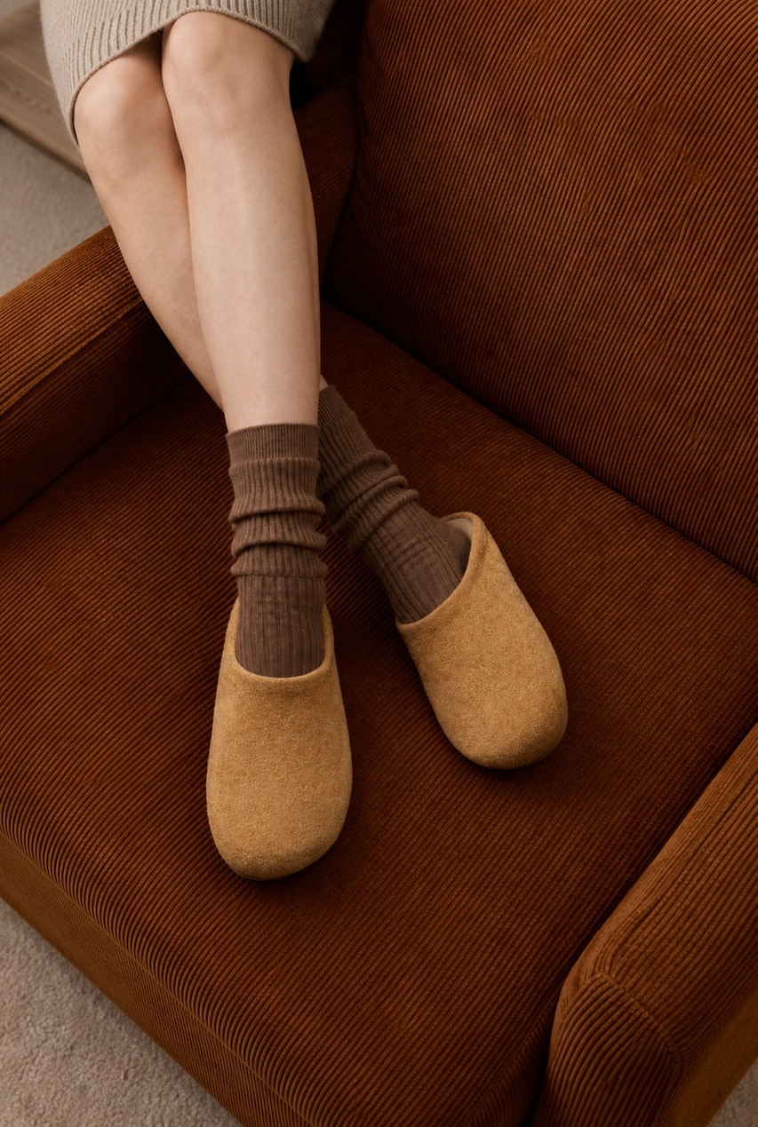 Round-Toe Clog Mules worn with warm socks on a brown sofa