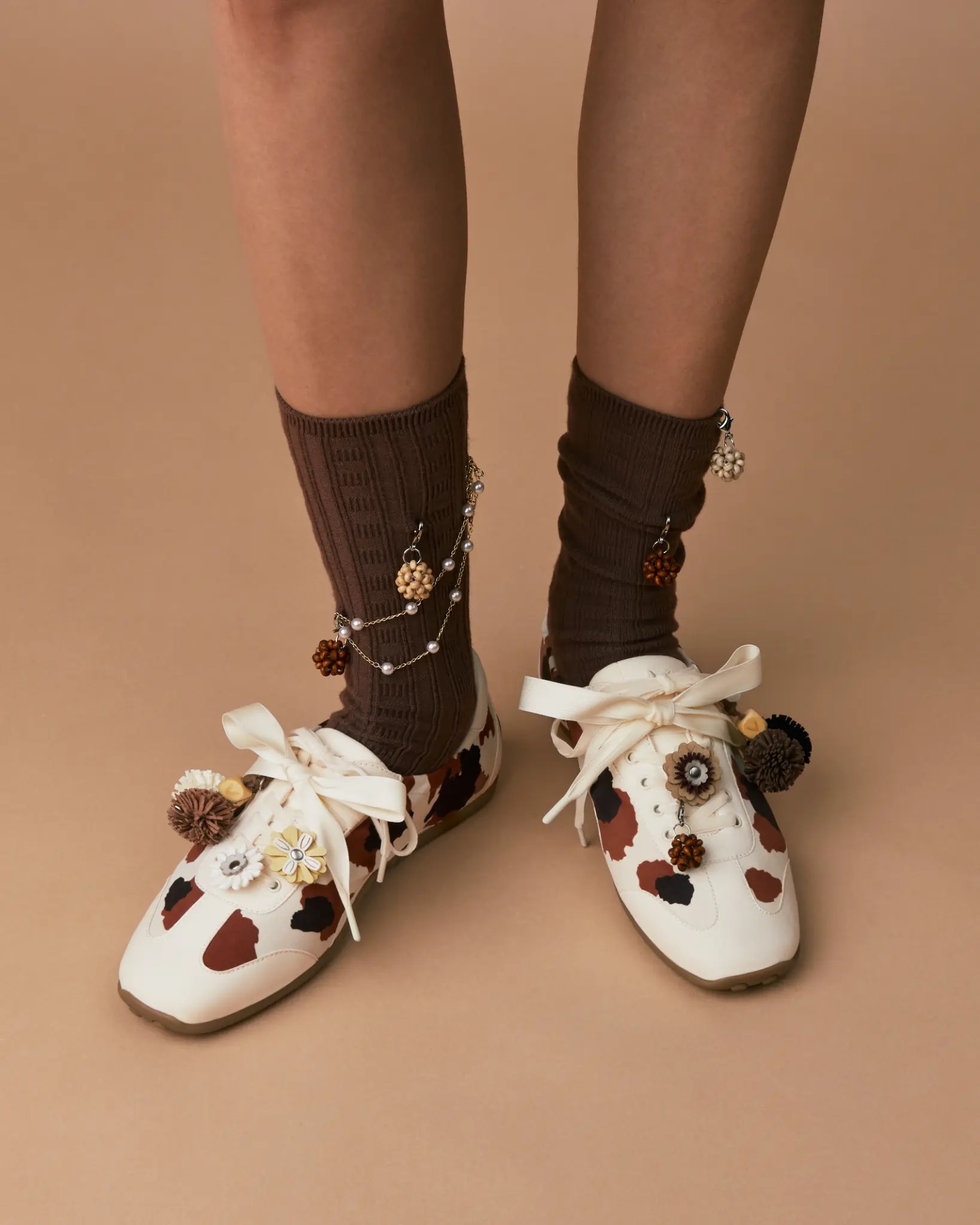 Model wearing cowhide VIVAIA sneakers with brown ribbed socks, white ribbons and autumn charms