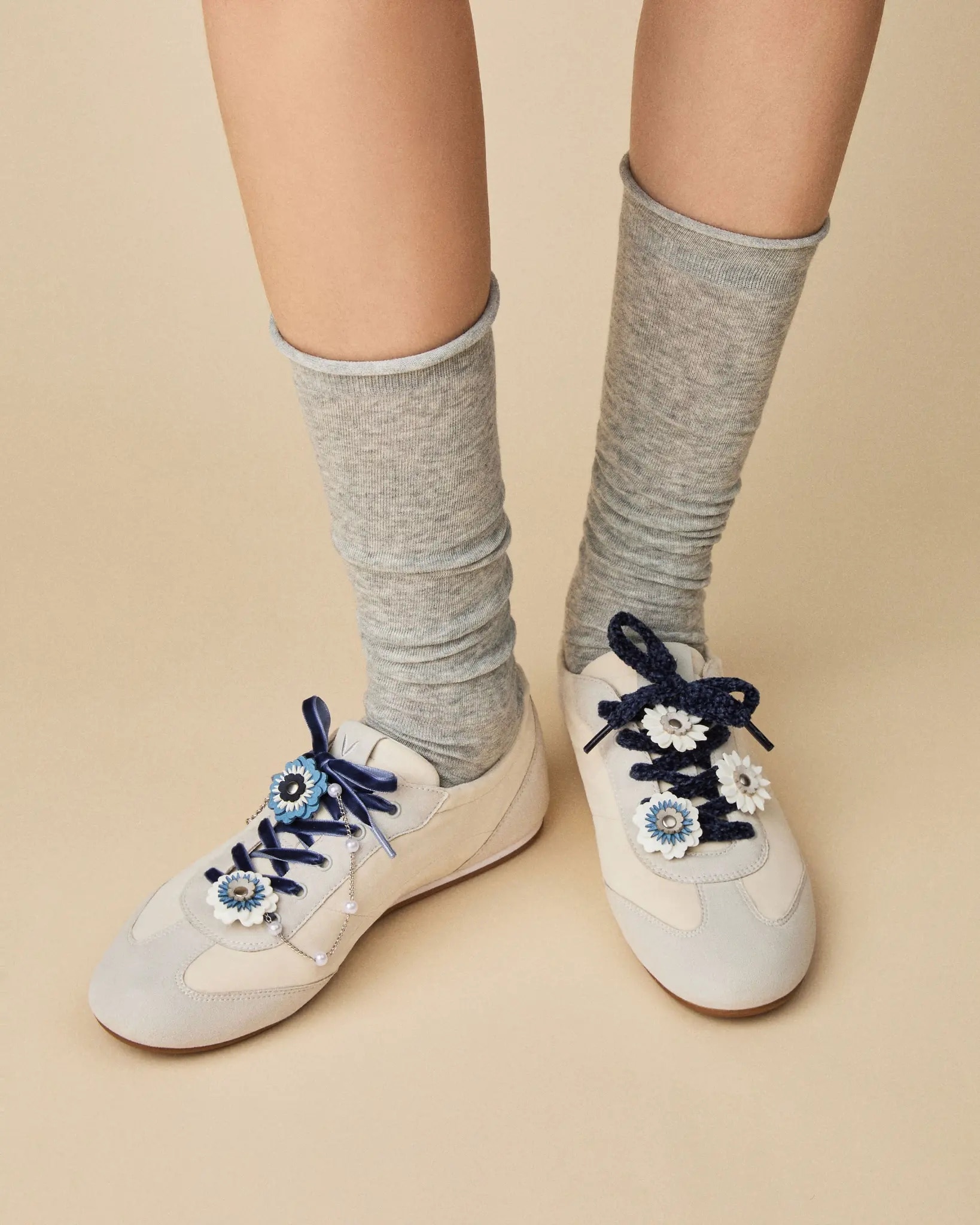 Model wearing white VIVAIA sneakers with grey socks, navy laces and blue flower charms