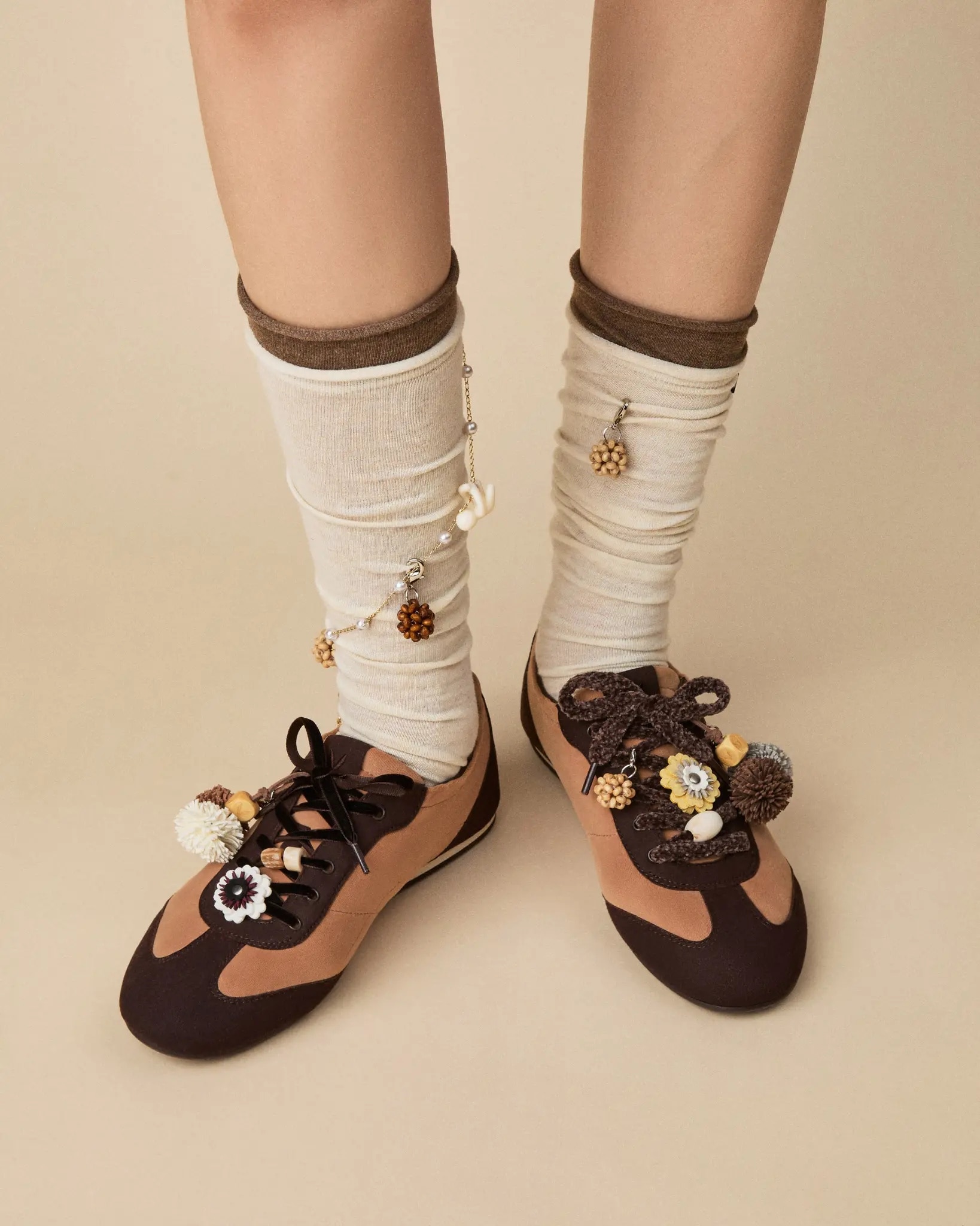 Model wearing brown and cream VIVAIA sneakers with cream socks and floral charms