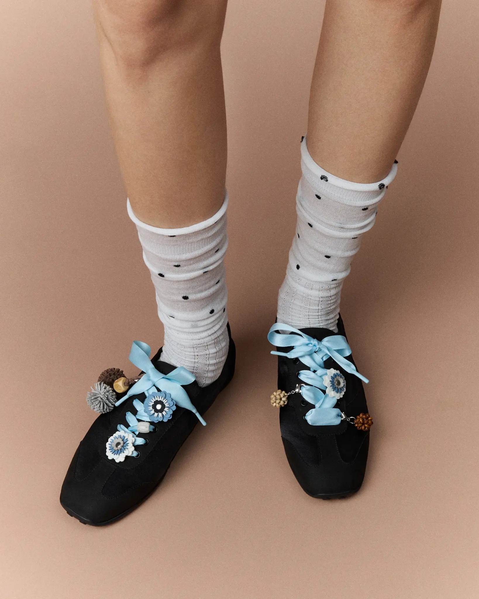 Model wearing black VIVAIA sneakers with white socks, blue ribbons and floral charms