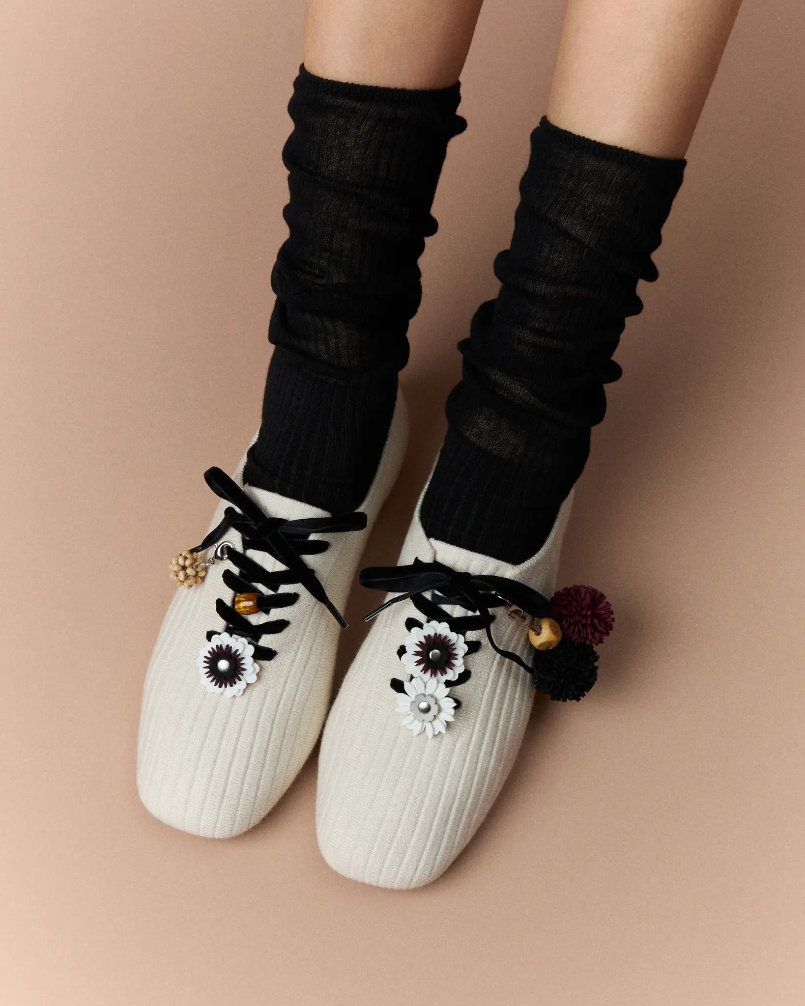 Model wearing cream VIVAIA knit flats with black socks and floral charms