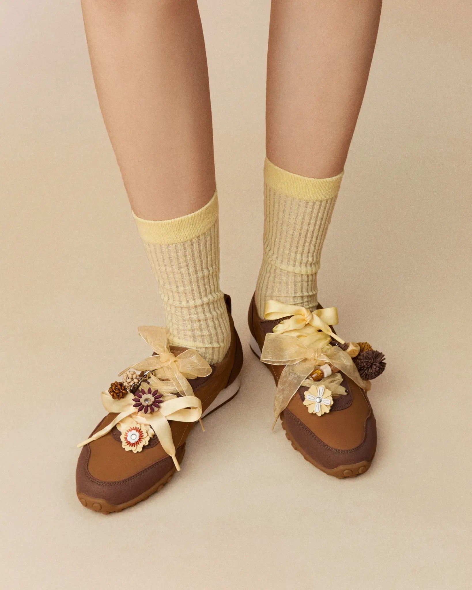 Model wearing brown VIVAIA sneakers with yellow socks, ribbons and autumn charms