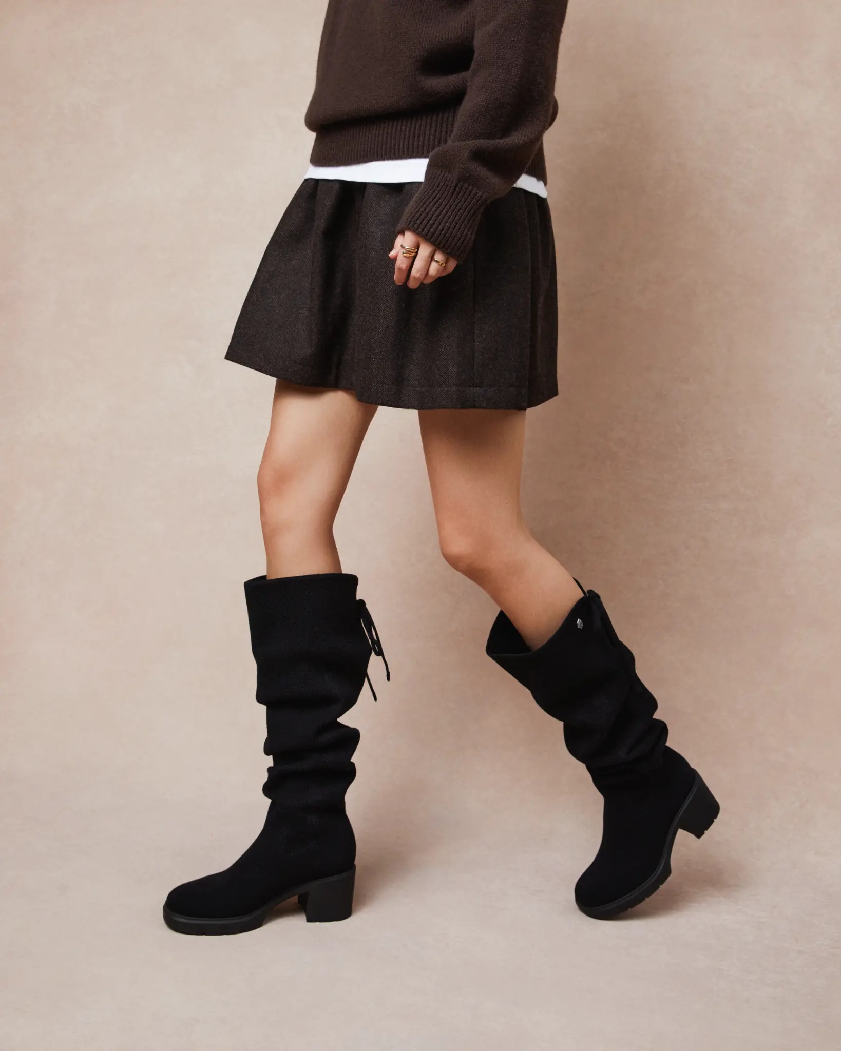 Black knit boots styled with a short skirt and dark knit sweater